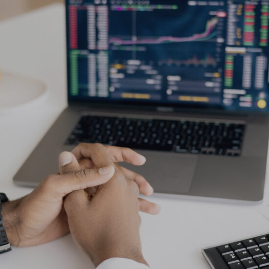 Dev Tech Solutions | Hands resting on a desk in front of a laptop displaying financial and performance graphs.