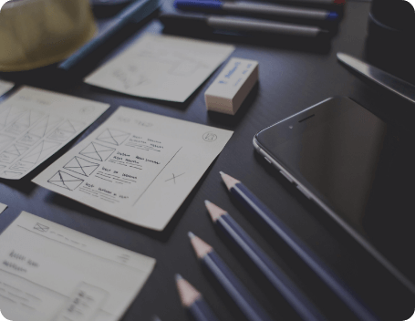 Dev Tech Solutions | Minimal website wireframes and sketch notes laid out neatly on a desk alongside pencils and a smartphone.