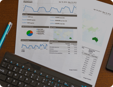 Dev Tech Solutions | Printed website performance dashboard with traffic charts and metrics placed on a desk beside a keyboard.