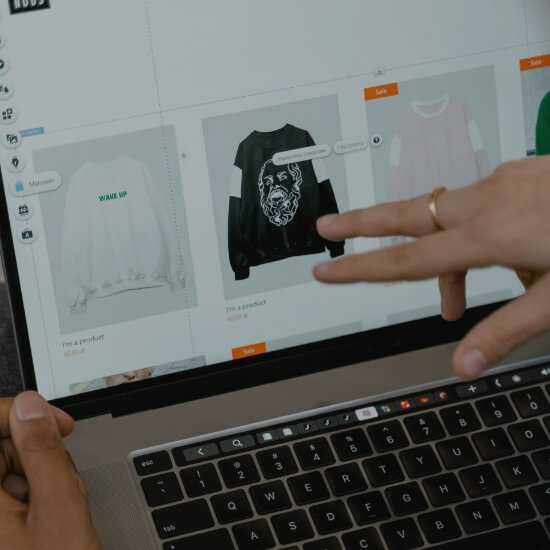 Dev Tech Solutions | Designer reviewing a product layout interface on a laptop with multiple items displayed.