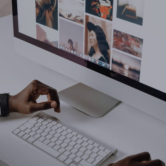 Dev Tech Solutions | Person working at a desktop computer with a clean image grid layout displayed on screen.